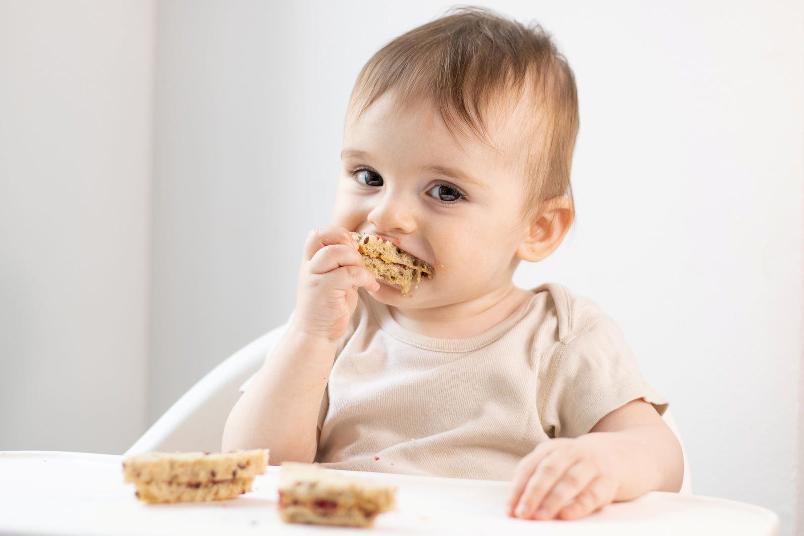 Baby eating a peanut butter sandwich as part of early peanut introduction