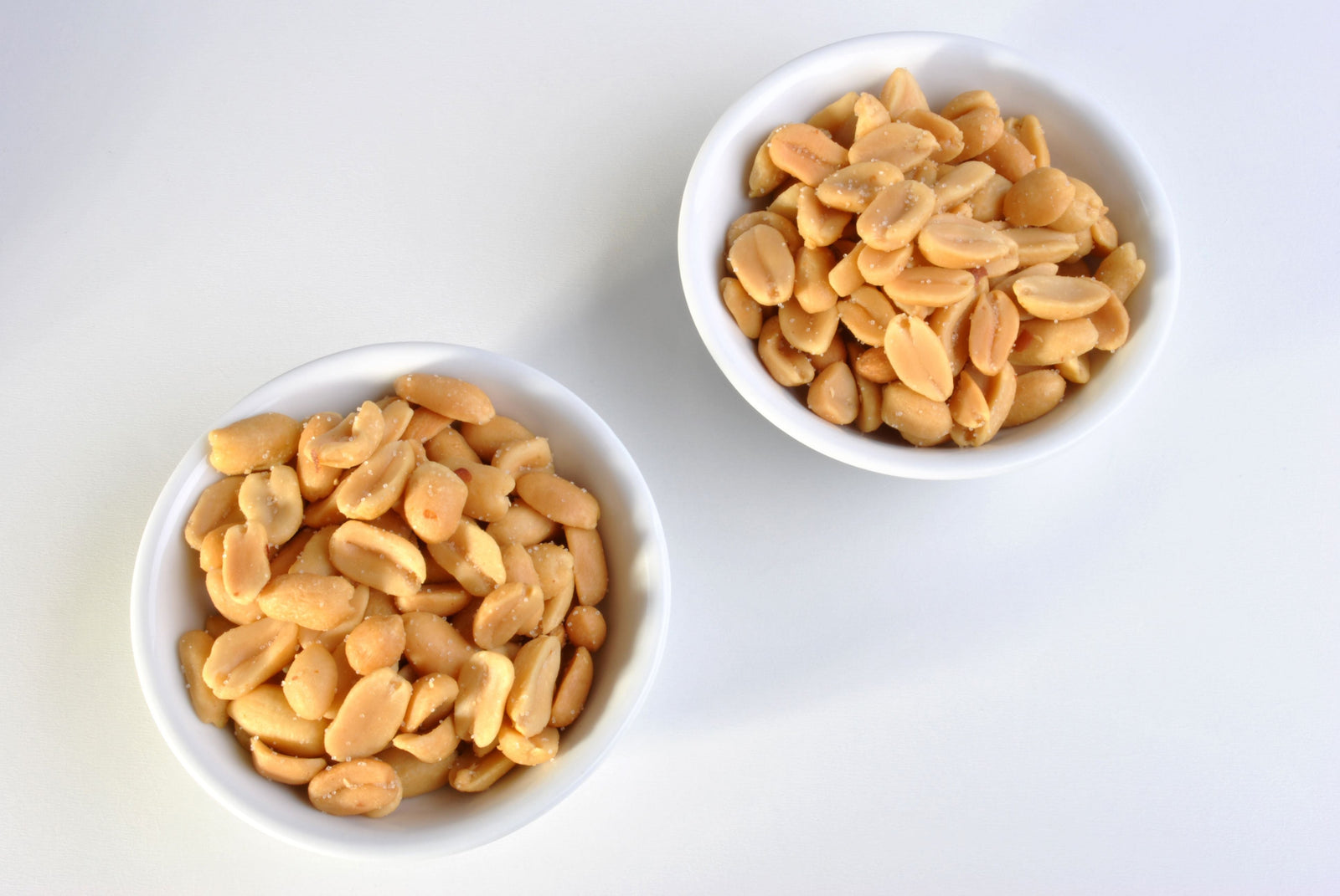 Side-by-side bowls of salted and unsalted peanuts comparing two everyday snacking options